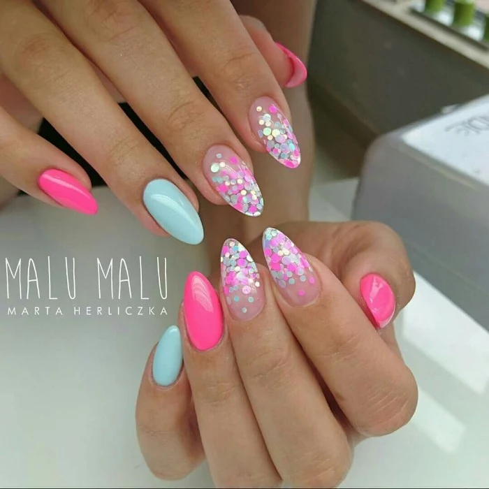turquoise blue and neon pink nail polish, on two hands with oval shaped nails, four of the nails are nude pink, and decorated with iridecent neon pink, and neon blue glitter flakes