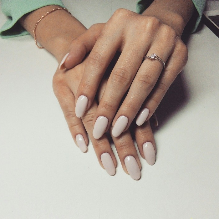 ivory colored nails, with an oval shape, on two hands, one resting on top of the other