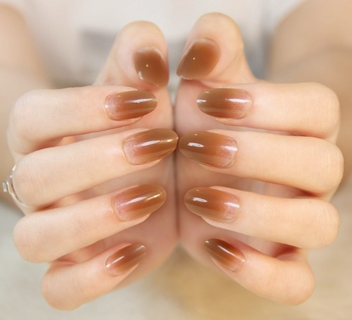 beige ombre-effect nail tips, decorating an oval manicure, with best nude nail polish, on two pale hands