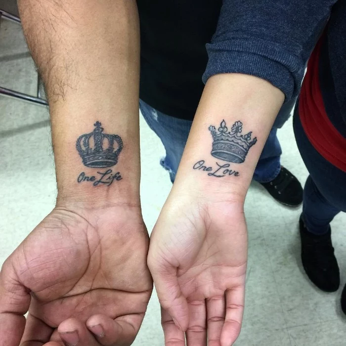 crowns for a king and a queen, tattooed near the wrists of two hands, together with the words one life, and one love, his and hers tattoos 