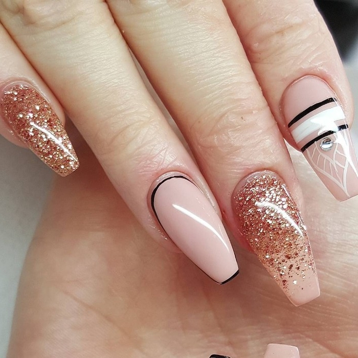 nude nail designs, long coffin shaped manicure, in nude pink, decorated with rose gold glitter, white and black stripes, and a silver gem sticker