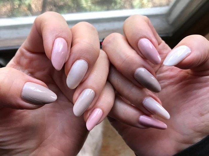 oval and long, nude gel nails, in pale pastel hues of pink, grey and white, on two hands with folded fingers