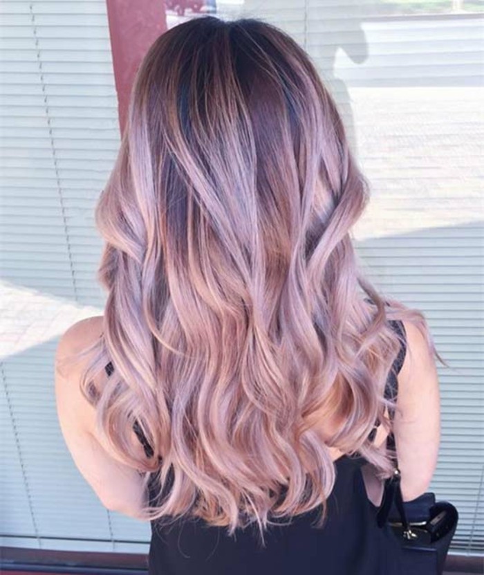 pastel pink balayage brown hair, with loose curls, worn by a woman in a black strappy top, with a bag on her shoulder