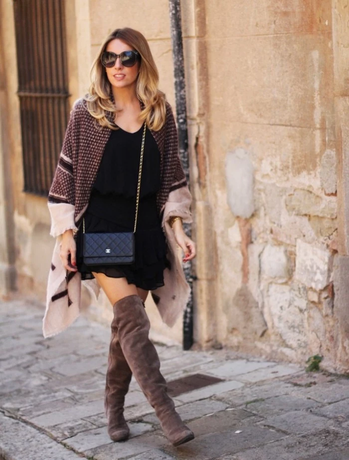 mink colored suede over the knee boots, paired up with a black mini dress, and accessorized with a patterned, ivory and dark grey blanket shawl, worn like a cardigan