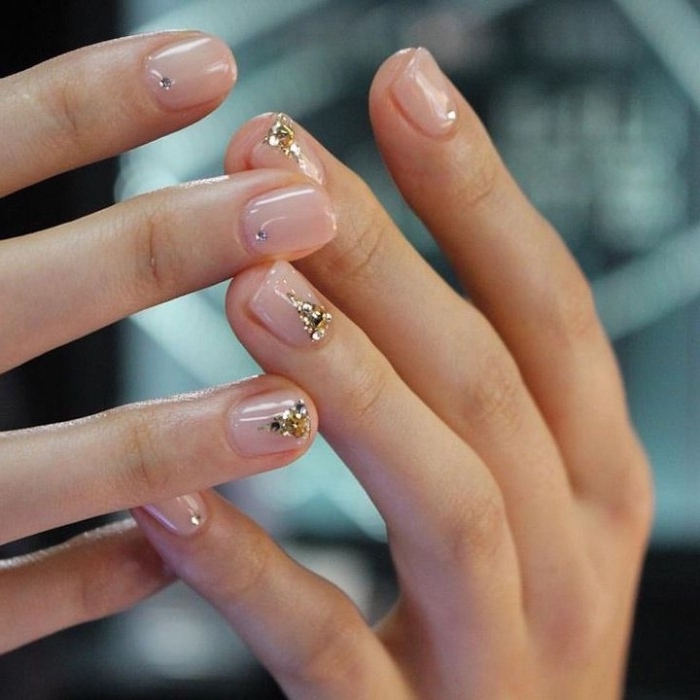 small gem nail decal stickers, in silver and gold, on the short, square nails of two hands,