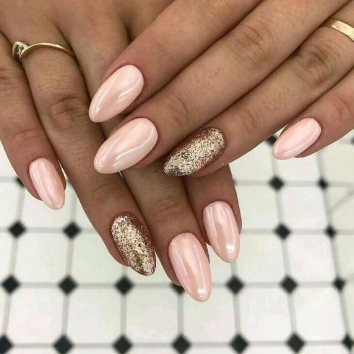 almond nail designs, in pearly pink, and gold glitter, worn by two slim tan hands, seen in close up