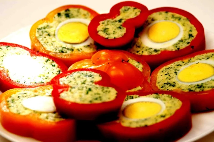 sliced pepper stuffed with seasoned mashed potato, and hardboiled eggs, on a white round dish