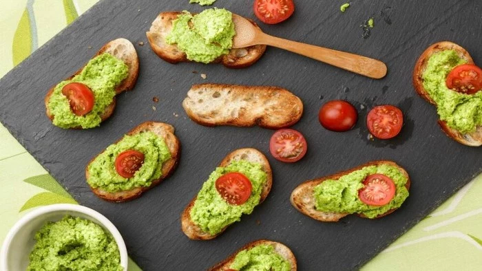 guacamole spread on several pieces of toasted bread, some are garnished with cherry tomatoes, cut in half, hors d oeuvres recipes, with fresh avocado