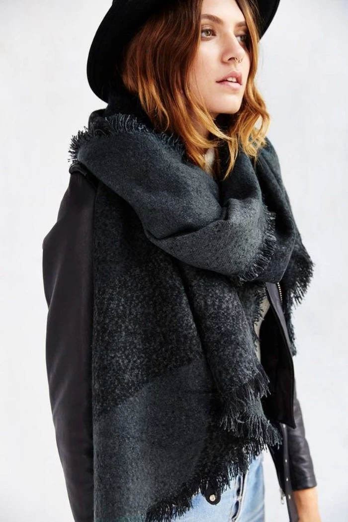charcoal grey oversized scarf, combined with a black felt hat, black leather jacket, and pale denim jeans, scarf outfits, worn by a young woman, with wavy shoulder length hair