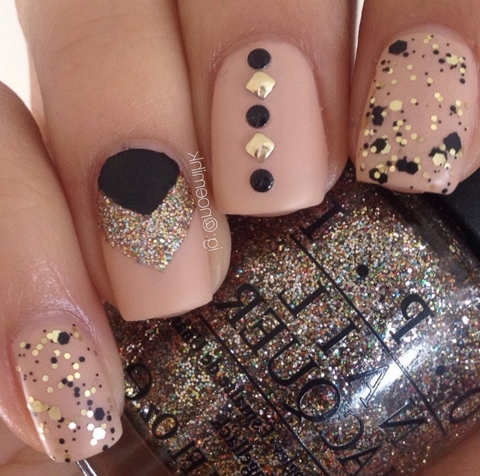 multicolored and gold glitter, stickers and splashes of black nail polish, decorating short and square, nude matte nails 