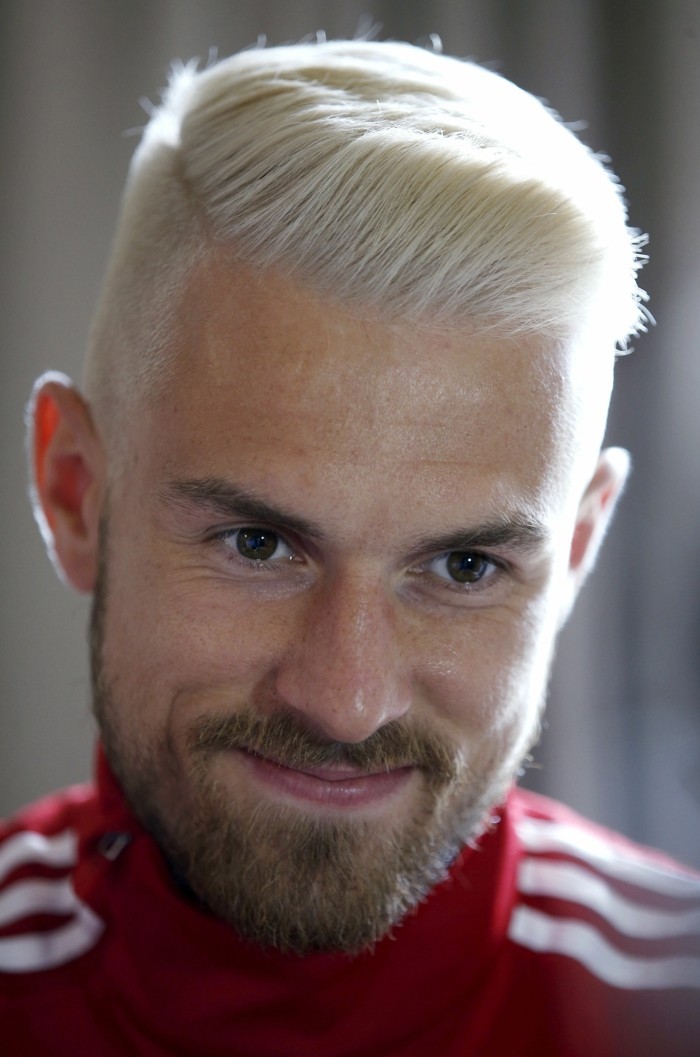red adidas tracksuit top, worn by a smiling man, with mustache and a beard, and platinym blonde hair, styled in a quiff