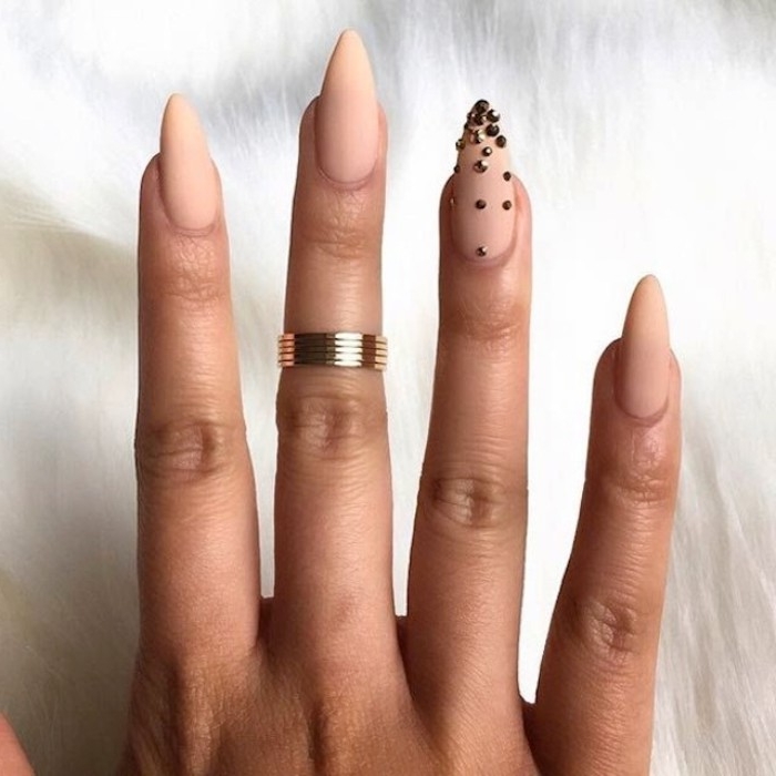 bead-like metallic nail decal stickers, decorating one of four, nude matte nails, on a hand with a gold ring