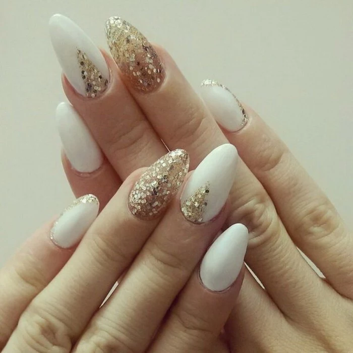 long oval nails, in white and gold, decorated with large glitter flakes, and seen in close up, on a white background