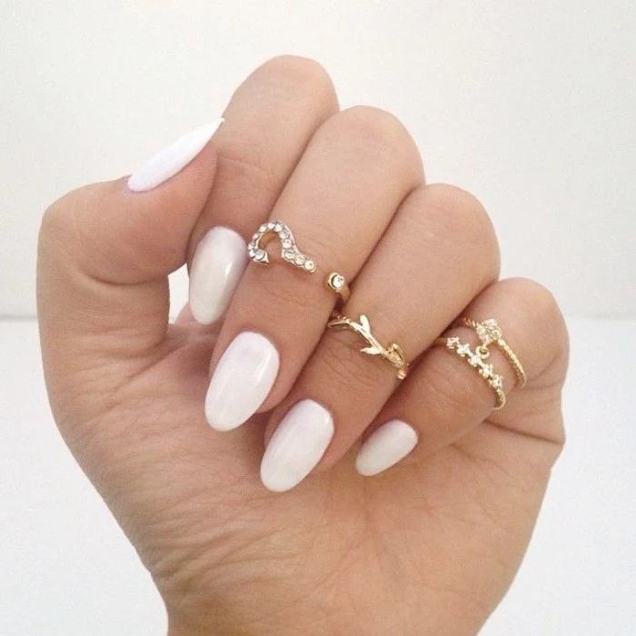 clear white nail polish, on pale fingers, decorated with several golden rings, almond nail designs, for everyday wear