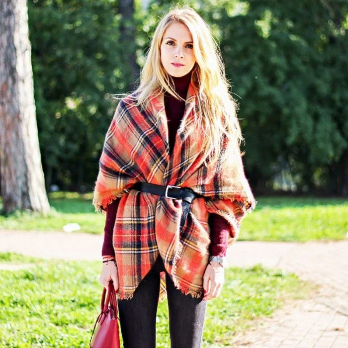 belt made from black leather, securing a red tartan oversized scarf, worn by a blonde woman, in a wine red jumper, and dark skinny jeans