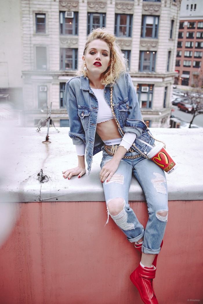 crop top in white, and pale distressed jeans, worn with a denim jacket, 80s clothes, by a blonde woman, with red sports shoes, and a novelty bag, shaped like a platic cup