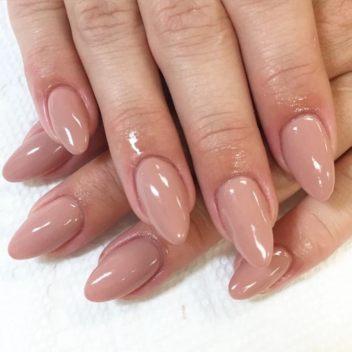 eight fingers with almond-shaped manicure, with smooth and glossy, nude pink nail polish, short pointy nails
