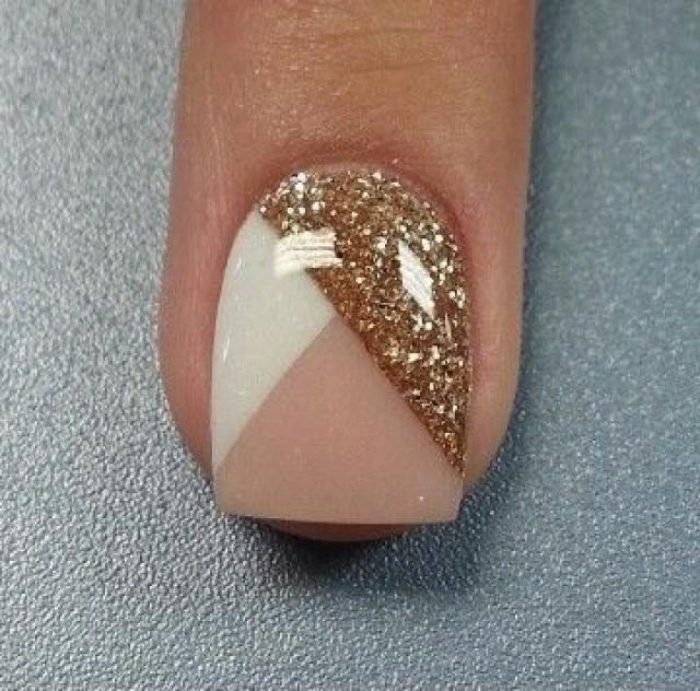 one short nail, with square tip, painted in nude pink, and white, and decorated with gold glitter