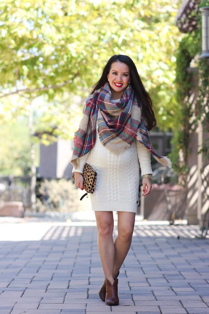 leopard print clutch bag, held by a smiling woman, dressed in a white knitted jumper, accessorized with a large plaid scarf, scarf outfits for warm fall days