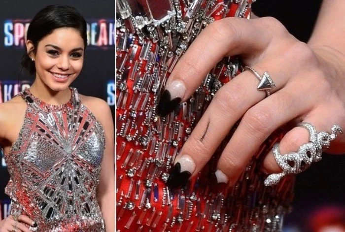 heart shapes in black, decorating the tips of a nude pink manicure, almond nail designs, worn by a smiling young woman, in a glittering silver dress