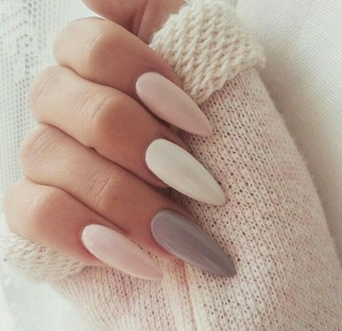 off-white fluffy sleeve, held by a hand, with a long and pointy manicure, white and pastel grey, and pink nude nails