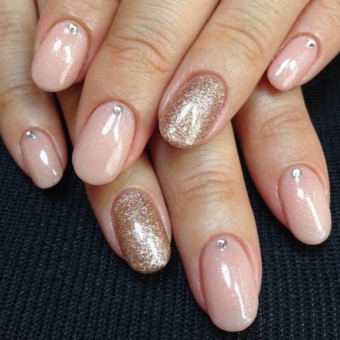 gem nail decals in silver, on an oval manicure, in pale pink, decorated with rose gold glitter, nude nails with glitter, on two hands, seen in close up