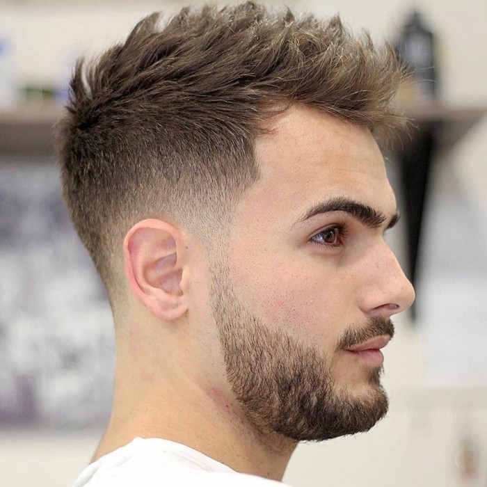 chectnut brown hair, styled in a spiky faux hawk, types of haircuts for men, worn by a young man, with a mustache and a beard
