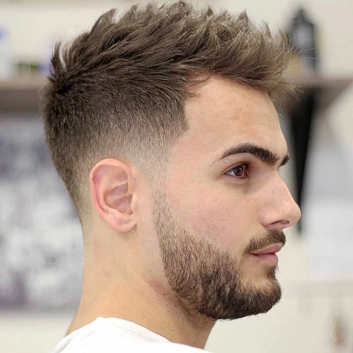 chectnut brown hair, styled in a spiky faux hawk, types of haircuts for men, worn by a young man, with a mustache and a beard