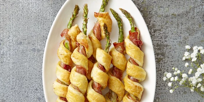 bacon and asparagus, wrapped in a pastry, hor d oeuvres ideas, placed in an oval white plate