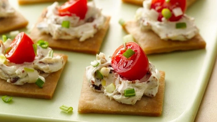 creamy spread with spring onions, on top of several square crackers, with cherry tomatos, hors d oeuvres recipes