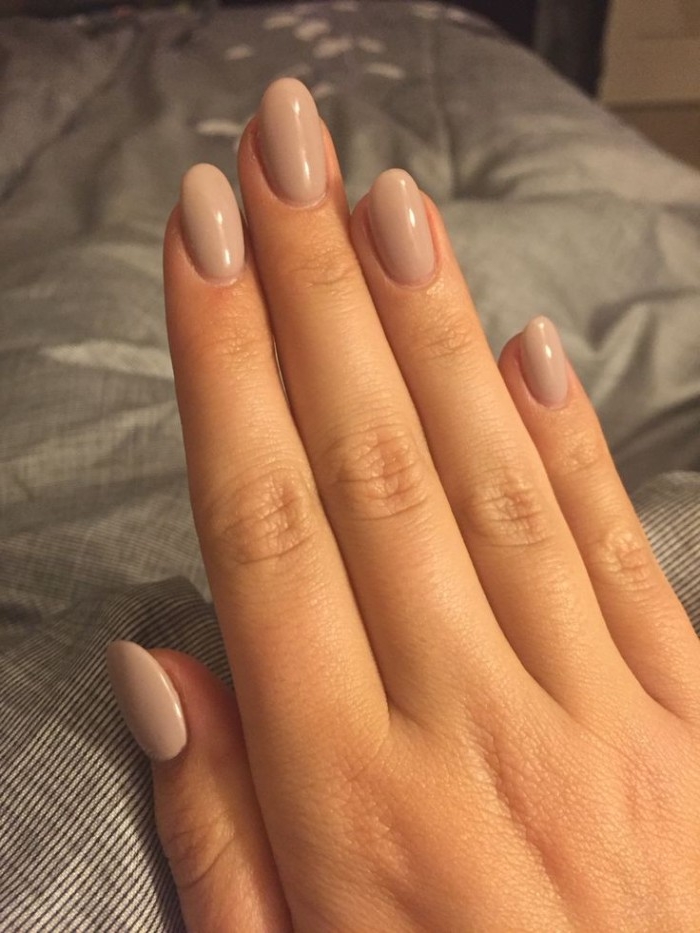 five fingers of a stretched out hand, with an oval manicure, painted in a beige, nude nail polish