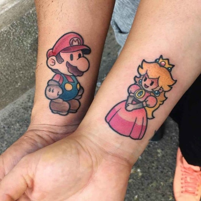 his and hers tattoos, princess peach and super mario tattoos, done in full color, near the wrists of two arms