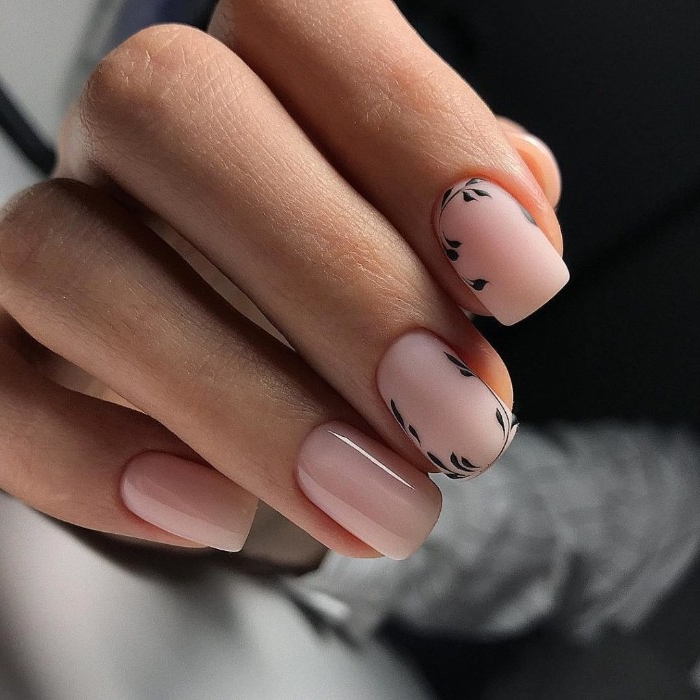 nude pink nail polish, on four nails, two plain and glossy, and two matte, and decorated with black, hand-drawn details