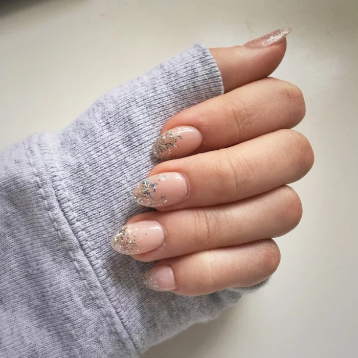 delicate short pointy nails, painted in nude pink nail polish, tips decorated with silver glitter