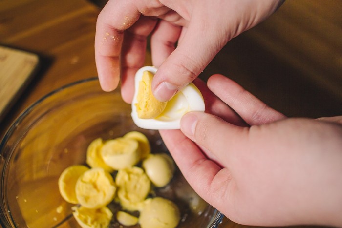 yolks from hardboiled eggs, inside a glass bowl, two hands separating a yolk from egg white, horderves easy recipes
