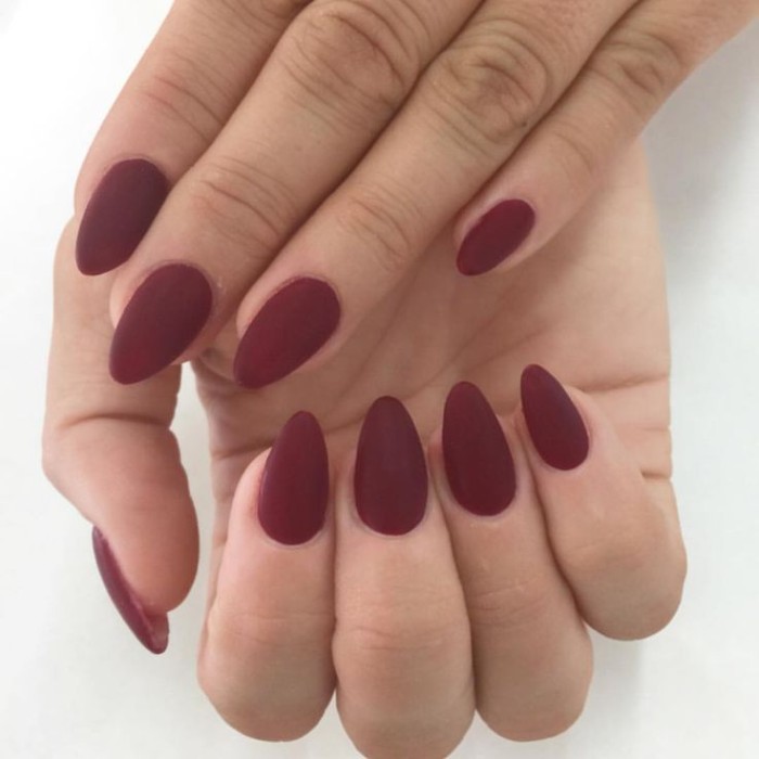 oxblood matte nail polish, on the short, pointy nails of two hands, seen in a close up, manicure ideas