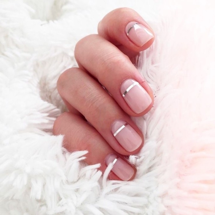 nude nails, each decorated with a thin, silver metallic stripe, on a hand, holding a white fluffy fabric