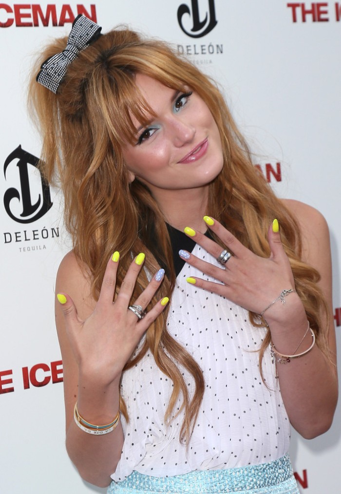 young woman with long, honey blonde hair, smiling while showing her manicure to the camera, yellow and silver nail polish, on oval shaped nails 