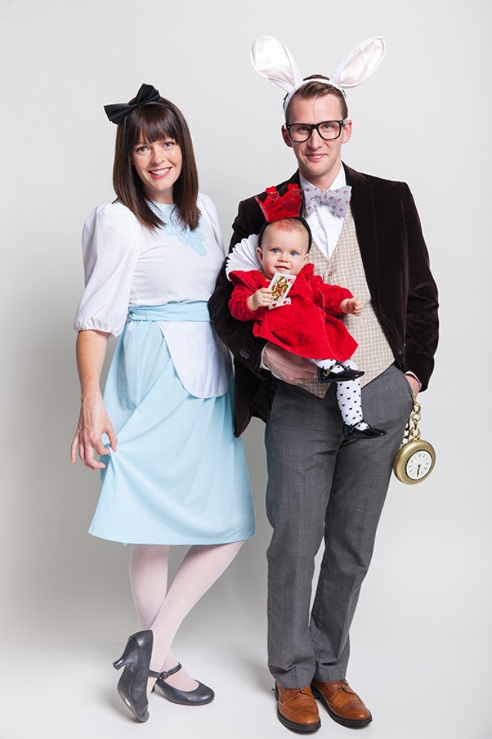 parents and a small baby, dressed like characters from alice in wonderland, the mother is alice, the father is the white rabbit, and the baby is the queen of hearts