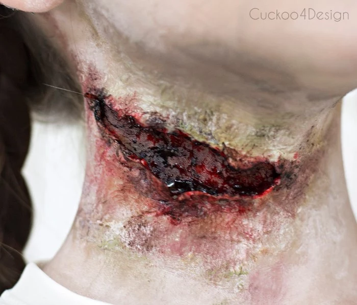 close up of a gory faux scar, facepaint ideas, created with special effects makeup wax, and fake blood, on the neck of a young girl