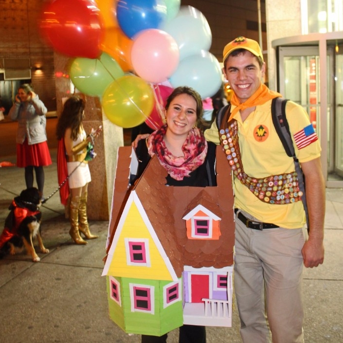 pixar's up inspired costumes, man dressed like a guilde, and a woman in a carboard house costume, decorated with many, multicolored balloons