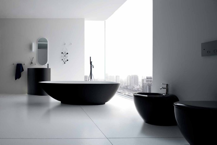 monochrome bathroom with white walls, black bathtub and sink, toilet and bidet, and two large windows