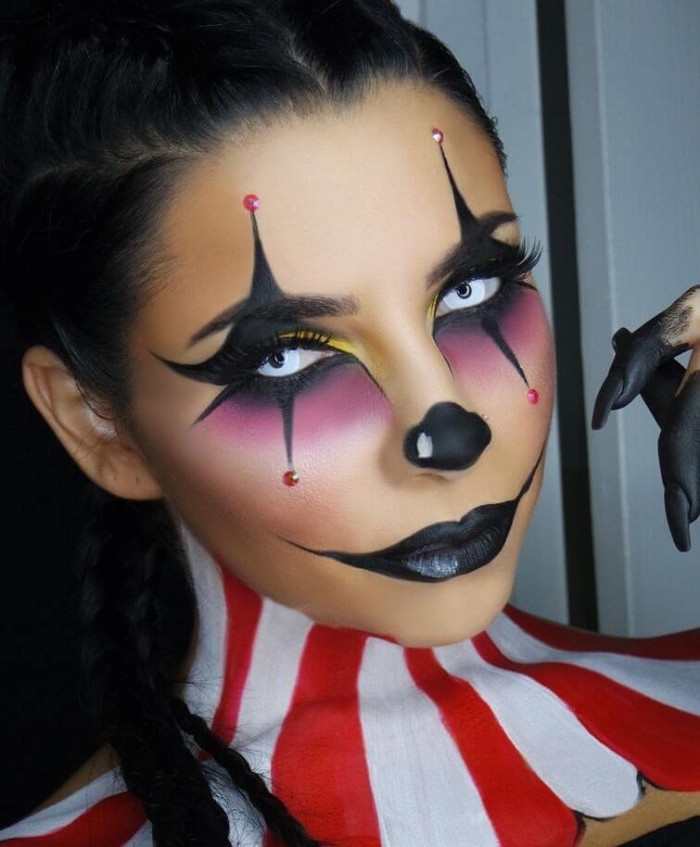 halloween face paint, young woman with clown makeup, in black and purple, wearing pale blue contact lenses, and black lipstick