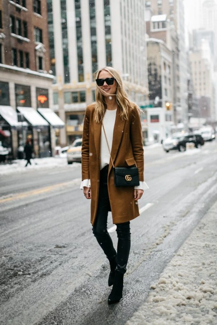khaki brown wool coat, worn over skinny, black leather trousers, and a plain white jumper, by a smiling blonde woman, with sunglasses and a black, cross body bag