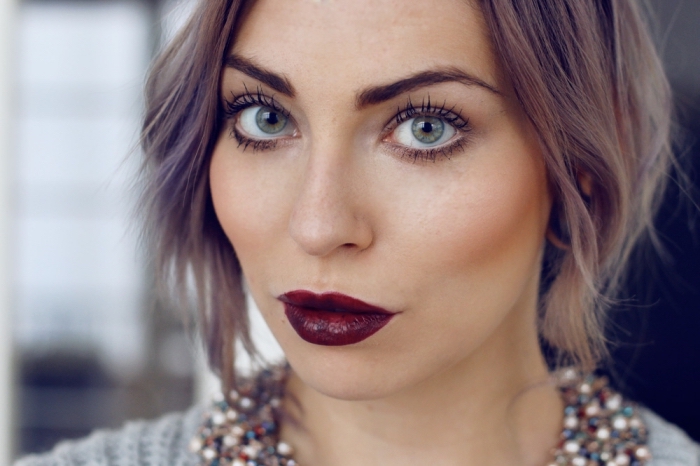 green-eyed woman, with light blonde hair, featuring bluish highlights, wearing cherry red lipstick