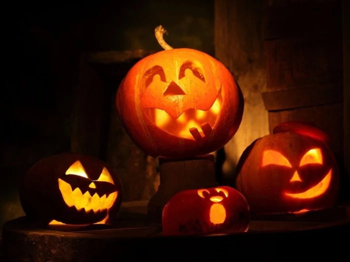 jack-o-lanterns carved from pumpkins, lit with candles from within, four traditional skeleton pumpkin lanterns