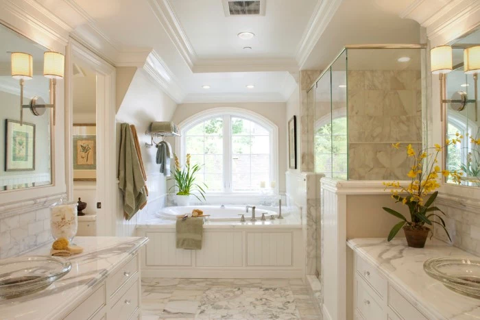 marble floor and wall tiles, inside a bright room, containing a round evevated tub, near a window, master bathroom remodel, two marble counter tops, with glass sinks