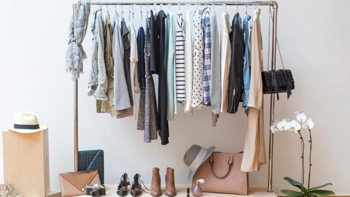 rack made of metal, with a few hangers, containing different clothes, how to create a minimalist wardrobe, shoes and bags nearby