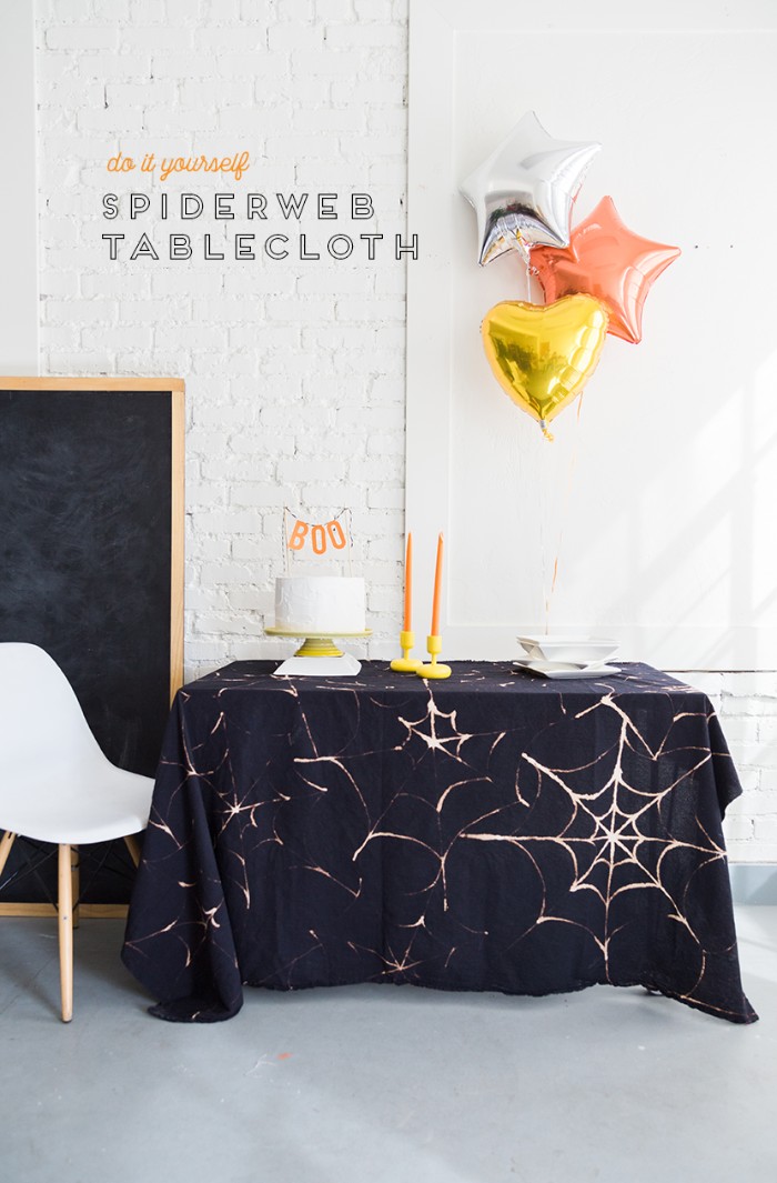 tablecloth in black, decorated with a pale, spider web pattern, made with bleach, halloween decorations, three balloons shaped like stars and a heart