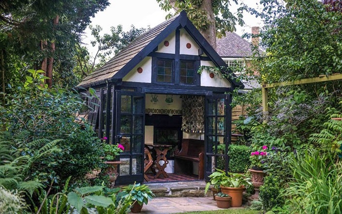 vintage cottage-style garden shed, in black and white, with open glass doors, revealing a rustic interior